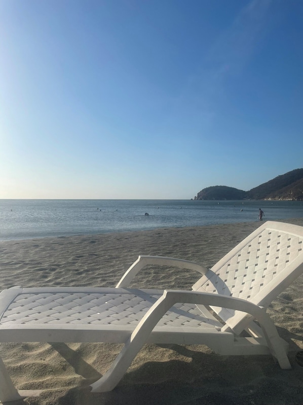 Une plage avec deux chaises longues blanches et une vue dégagée sur la mer.