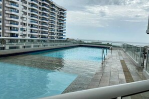 A swimming pool with a glass railing, a clear sky, and a high-rise building in the background. - Areia Beach - Pozos Colorados - Santa Marta - Colombia (Santa Marta)