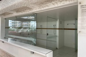 Une salle de bain moderne avec des douches à parois de verre, un lavabo blanc et un sol carrelé.