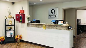 A hotel reception desk with a 'Quality by Choice Hotels' sign, a computer, a phone, and a coffee machine. - Quality Inn & Suites Prestonsburg (Prestonsburg)