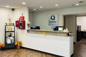 A hotel reception desk with a 'Quality by Choice Hotels' sign, a computer, a phone, and a coffee machine. - Quality Inn & Suites Prestonsburg (Prestonsburg)