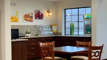A modern kitchen with wooden cabinets, a granite countertop, and a dining area with four wooden chairs.