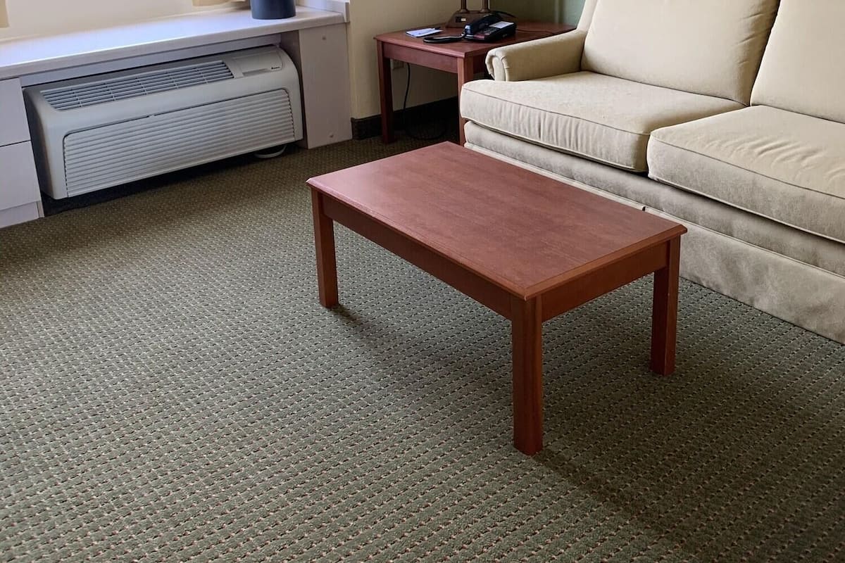Une pièce avec une fenêtre, un canapé, une table, une lampe et un radiateur.