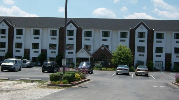 A multi-story hotel with a central entrance, parking lot, and several vehicles. - Quality Inn & Suites Prestonsburg (Prestonsburg)