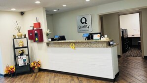 Taulell de recepció d'hotel amb un cartell de 'Quality by Choice Hotels', una caixa d'informació vermella i un mostrador de recepció.