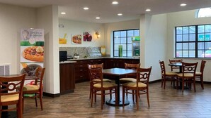 A restaurant interior with wooden flooring, a central dining table, and chairs. - Quality Inn & Suites Prestonsburg (Prestonsburg)