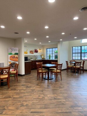 A restaurant interior with wooden flooring, a central dining table, and chairs. - Quality Inn & Suites Prestonsburg (Prestonsburg)