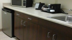 A kitchen with dark wooden cabinets, a microwave, a coffee maker, and a dishwasher. - Quality Inn & Suites Prestonsburg (Prestonsburg)
