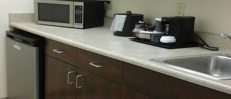 A kitchen with dark wooden cabinets, a microwave, a coffee maker, and a dishwasher.