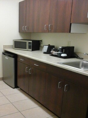 A kitchen with dark wooden cabinets, a microwave, a coffee maker, and a dishwasher. - Quality Inn & Suites Prestonsburg (Prestonsburg)