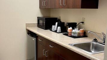 A kitchen with a microwave, coffee maker, and a sink.