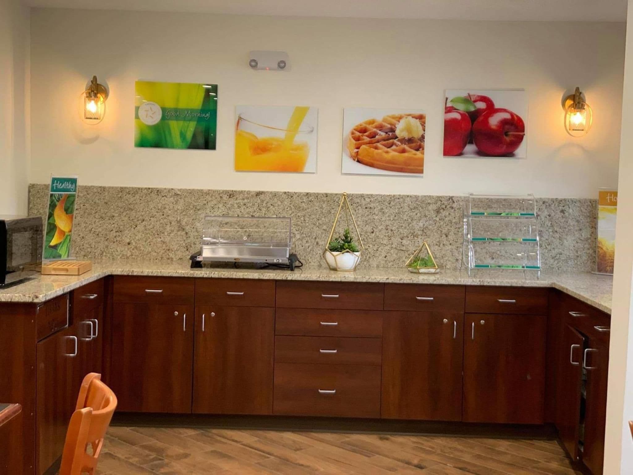 A kitchen with granite countertops, wooden cabinets, and wall-mounted light fixtures.