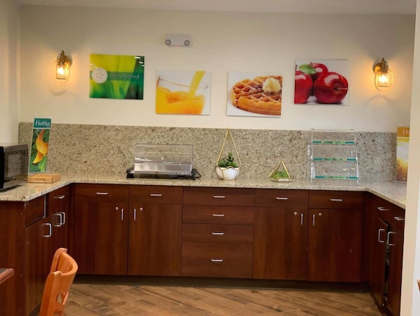 A kitchen with granite countertops, wooden cabinets, and wall-mounted light fixtures.
