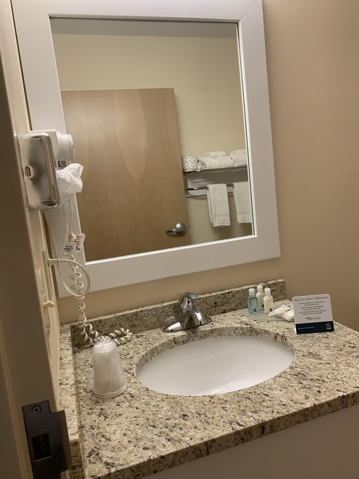 A bathroom with a sink, mirror, towel rack, and a hand dryer.