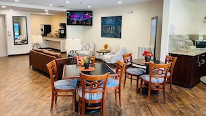 A hotel room with a dining area, a sofa, a TV, and a painting on the wall. - Quality Inn & Suites Prestonsburg (Prestonsburg)