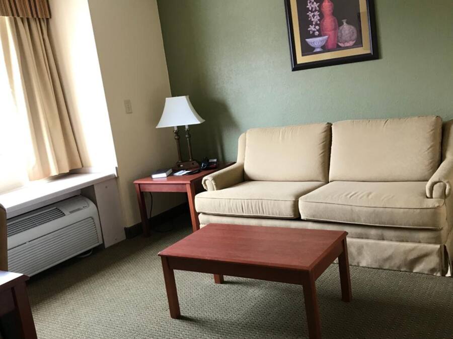 A living room with a beige sofa, a wooden coffee table, a lamp on a side table, and a framed picture on the wall.