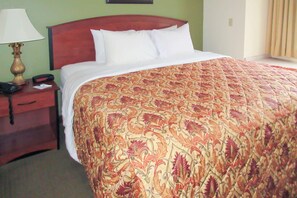 A hotel room with a large bed, a wooden headboard, a nightstand with a lamp, and a telephone. - Quality Inn & Suites Prestonsburg (Prestonsburg)