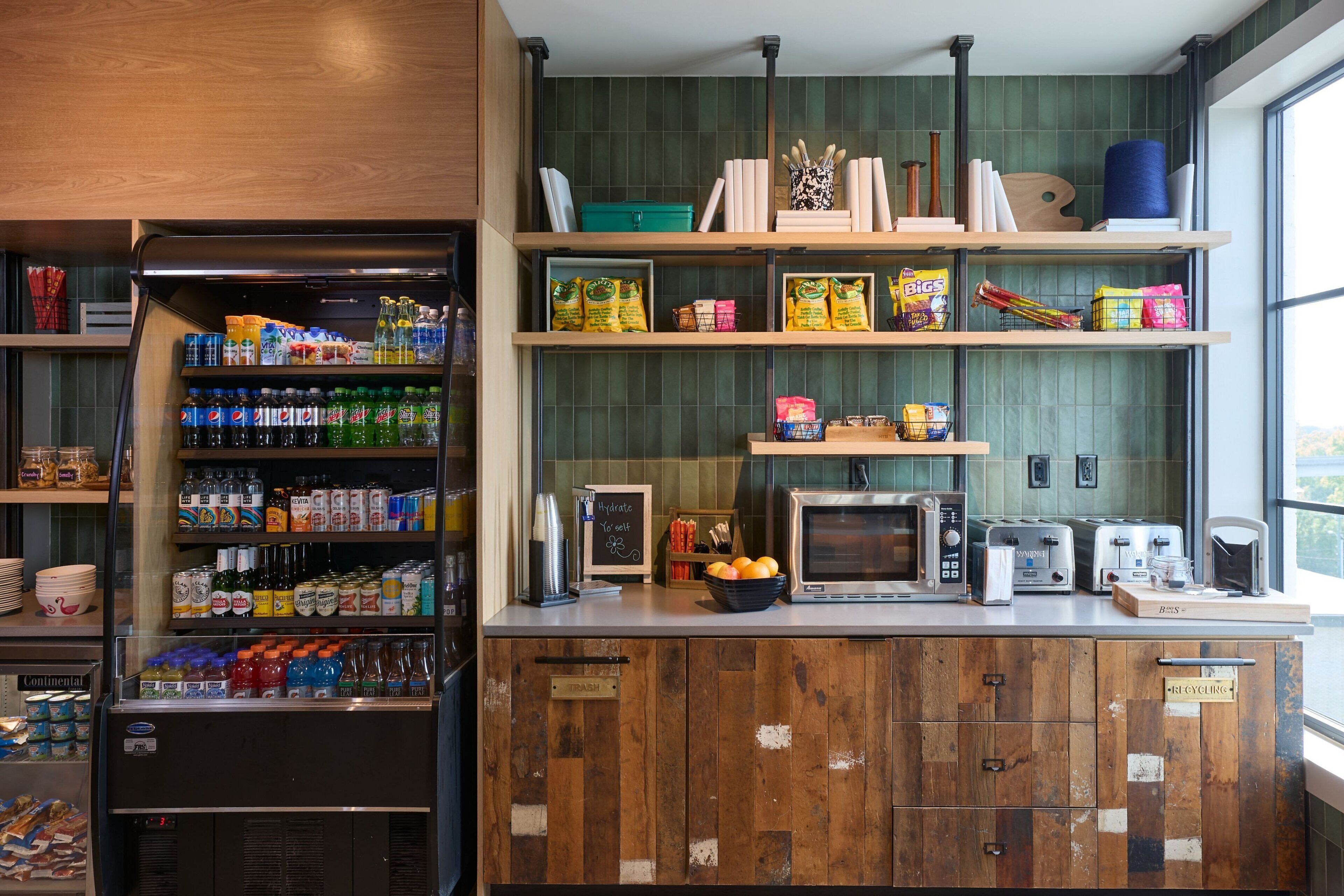 A kitchen with a refrigerator stocked with beverages, a microwave, and a toaster.