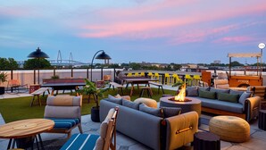 An outdoor seating area with a fire pit, lounge chairs, and a dining table. - Moxy Charleston Downtown (Charleston)