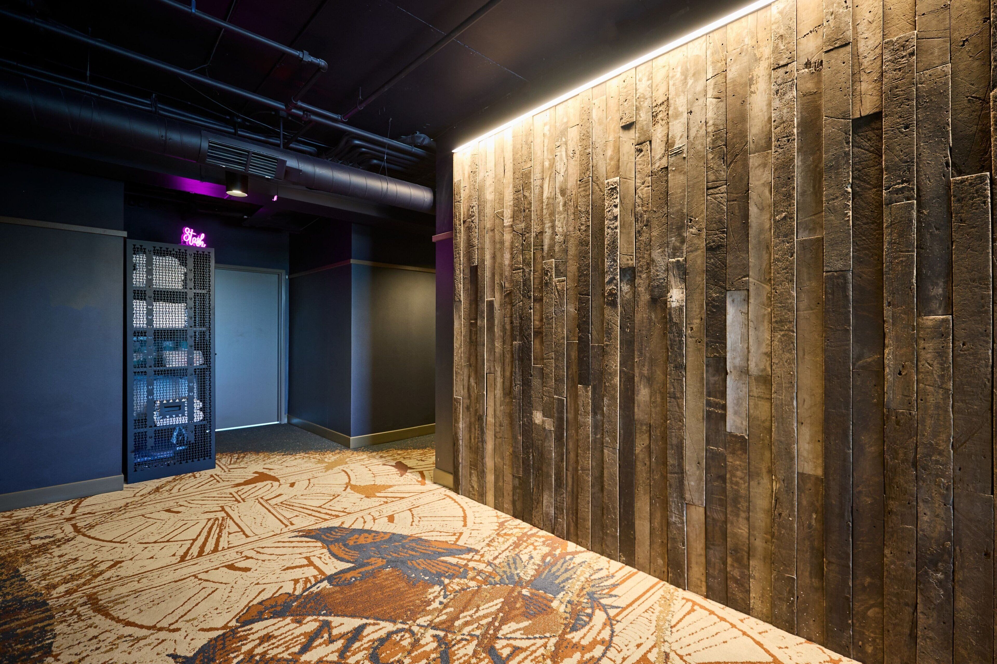 A modern lobby with a wooden wall and a patterned carpet.