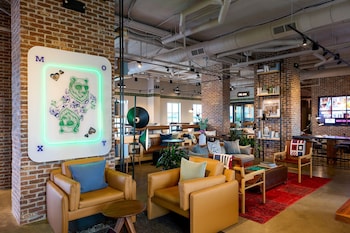 A multi-story hotel with a modern design, featuring a prominent entrance with glass doors and a neon sign. at Moxy Charleston Downtown