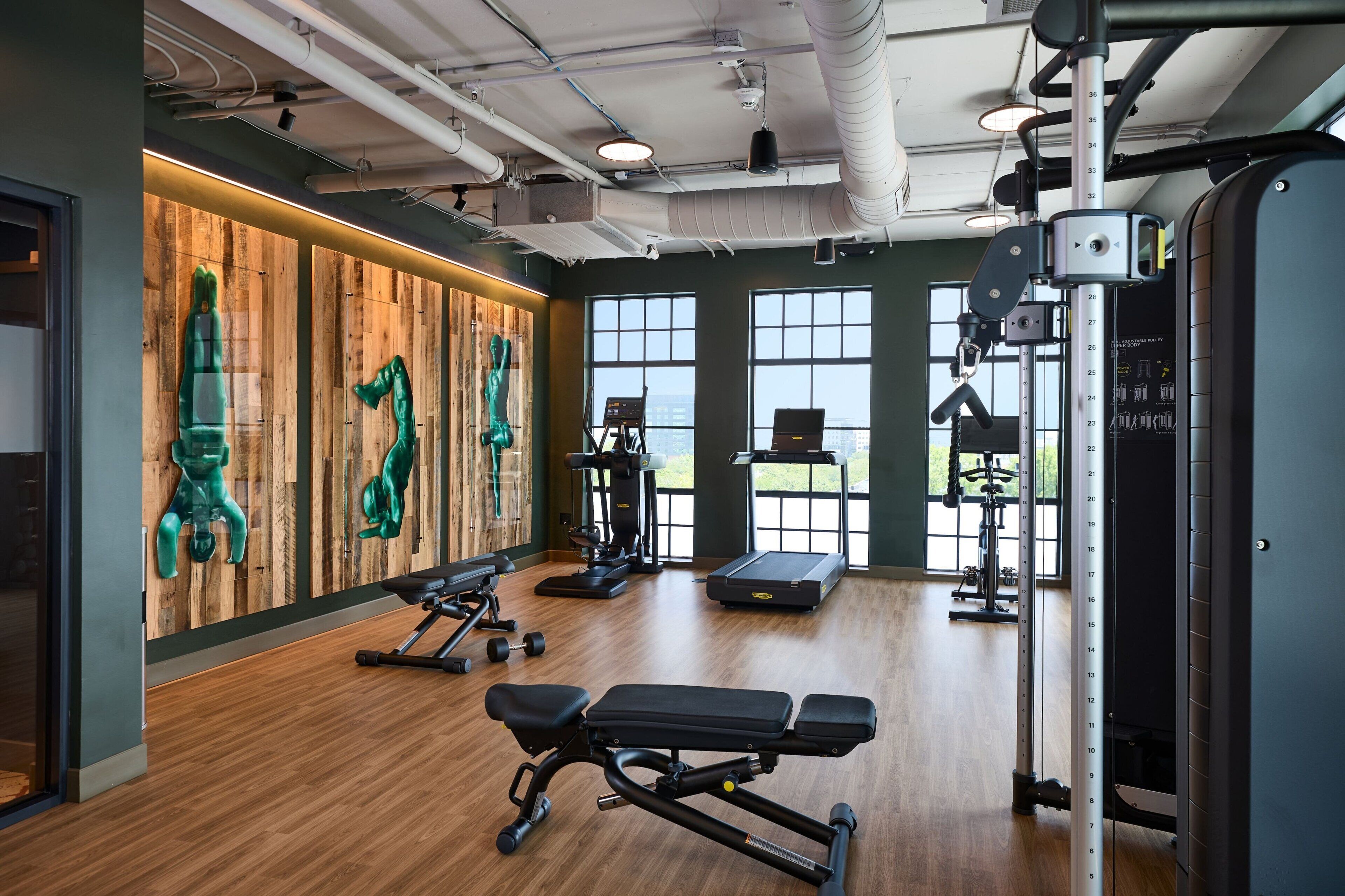 A gym with wooden walls, exercise equipment, and large windows.