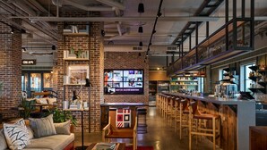 Un área de bar moderna con pared de ladrillo, mostrador de madera y varios taburetes.