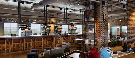 A modern bar with a brick wall, wooden furniture, and a variety of seating options.