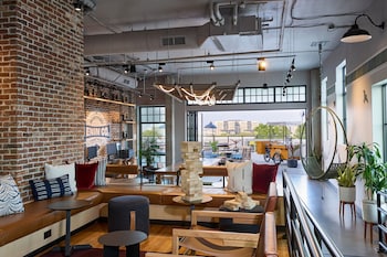 A corridor with a view of a cityscape through large windows, a chair, and a table. at Moxy Charleston Downtown