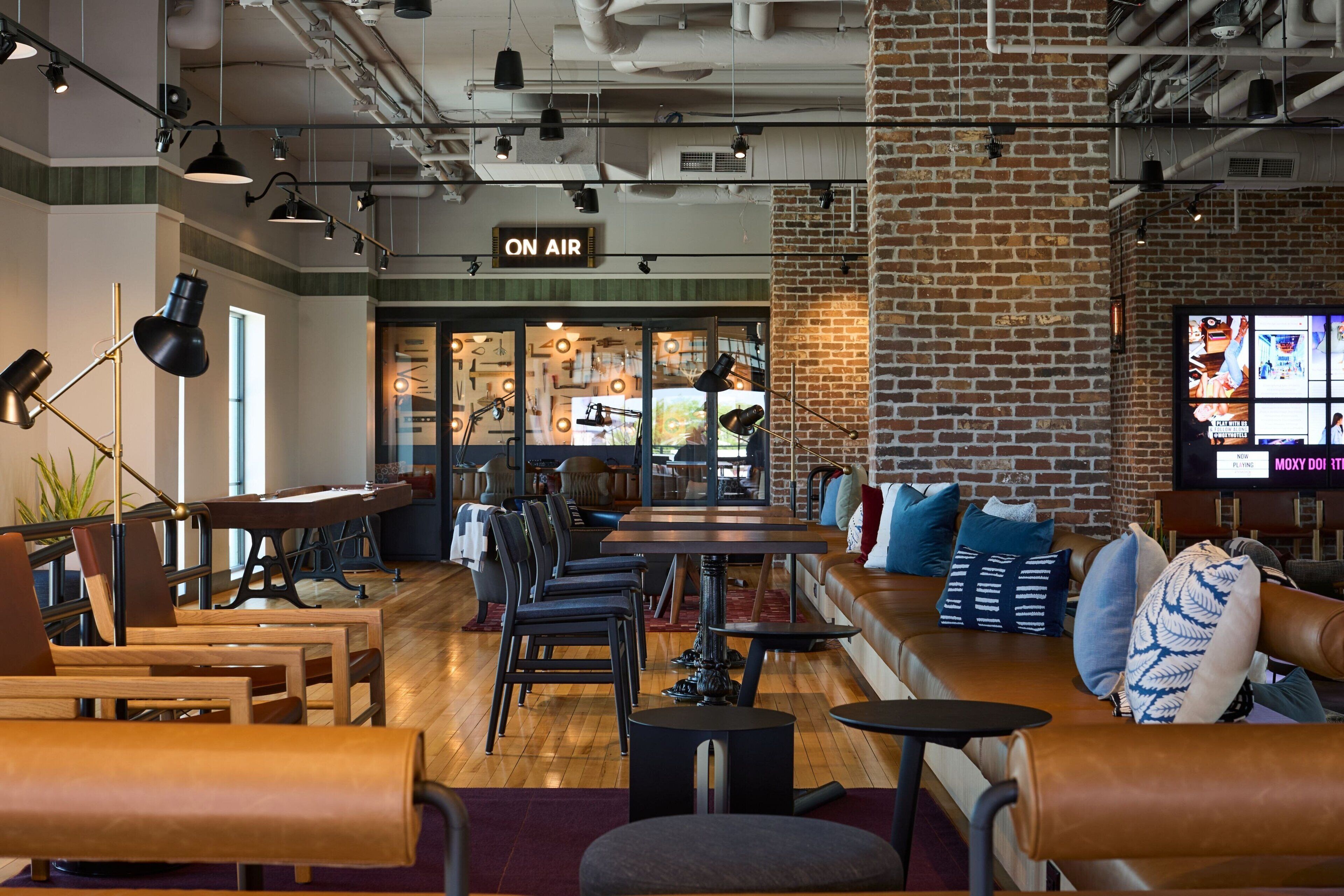 A modern lounge area with leather seating, a bar, and a visible 'ON AIR' sign.
