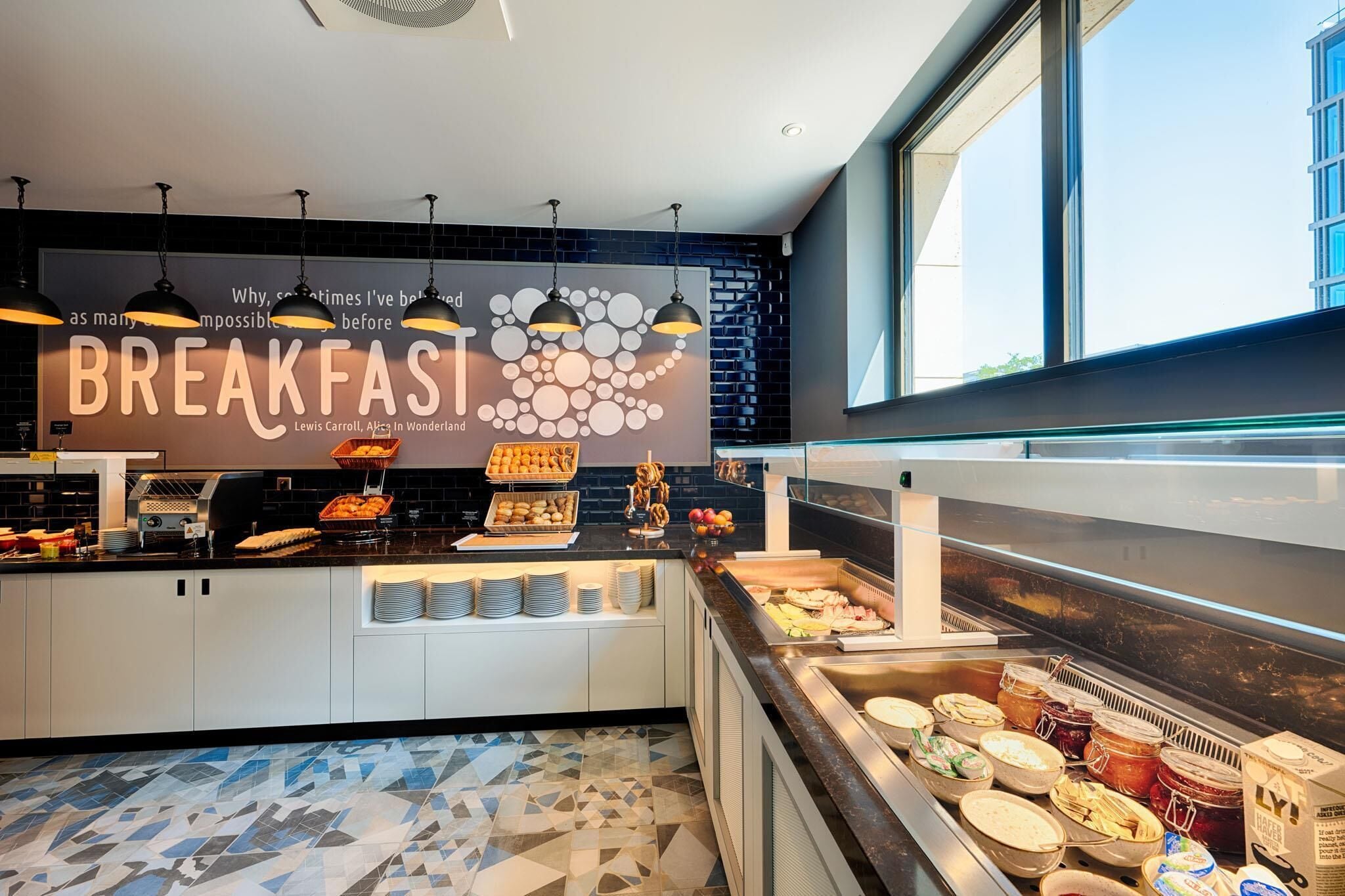 A breakfast buffet with a large sign, various food items, and a modern design.