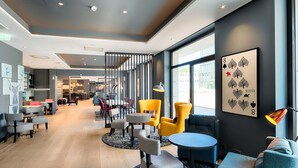 Un moderno vestíbulo de hotel con zonas de estar, una escalera y grandes ventanales.