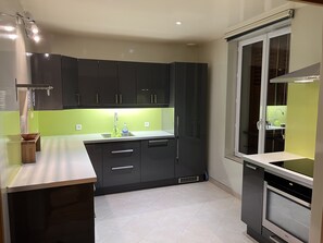 Uma cozinha moderna com armários escuros, painel de fundo verde e forno embutido.
