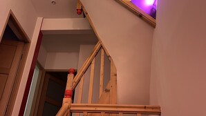 A wooden staircase with a handrail and a red handrail end cap. - Air-conditioned house near RER / Paris / Disney / CDG (Gagny)