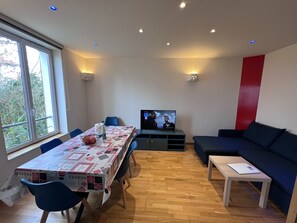 Uma sala de estar moderna com área de jantar, televisão e sofá.