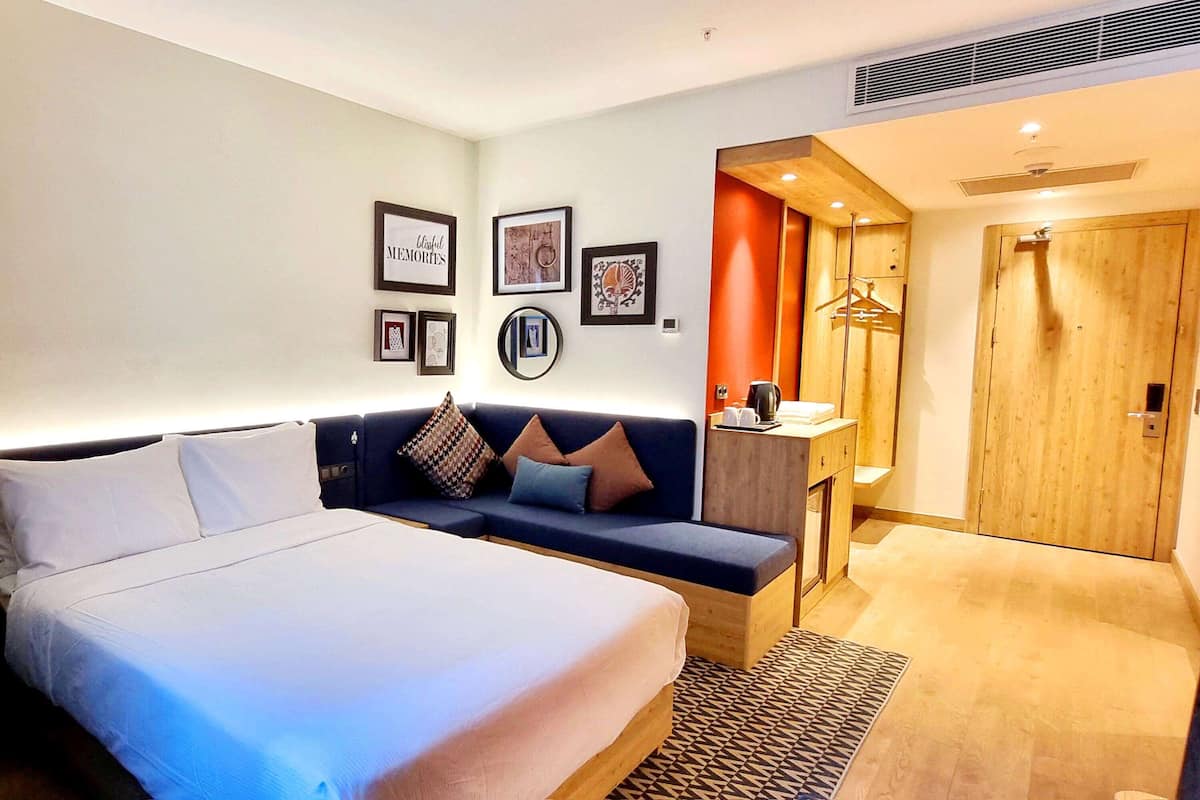 Una habitación de hotel con una cama grande, un sofá, un escritorio pequeño y un armario.
