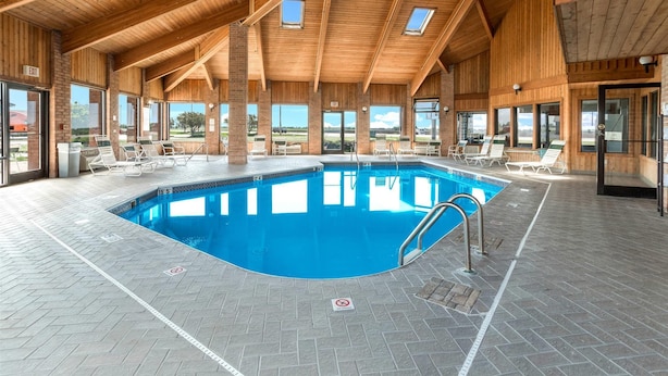 Une piscine intérieure avec un plafond en bois, de grandes fenêtres et des chaises longues.