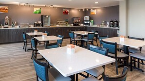 Un restaurant moderne doté de nombreuses tables et chaises, d’un comptoir avec une machine à café et de divers produits alimentaires exposés.