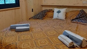 Ein Schlafzimmer mit Holzwänden, einem Bett, Kissen und einer Deckenleuchte.