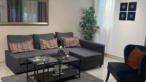 Un salon moderne avec un canapé gris, une table basse et un fauteuil bleu.