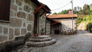 A stone building with a cobblestone path leading to a wooden door. - The Farmhouse I (Porto)