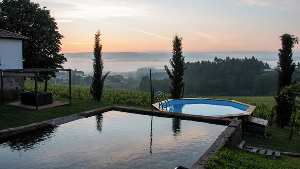 A swimming pool with a view of a misty landscape and distant hills. - The Farmhouse I (Porto)
