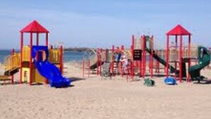 Une aire de jeux de plage avec des toboggans et des structures d’escalade.