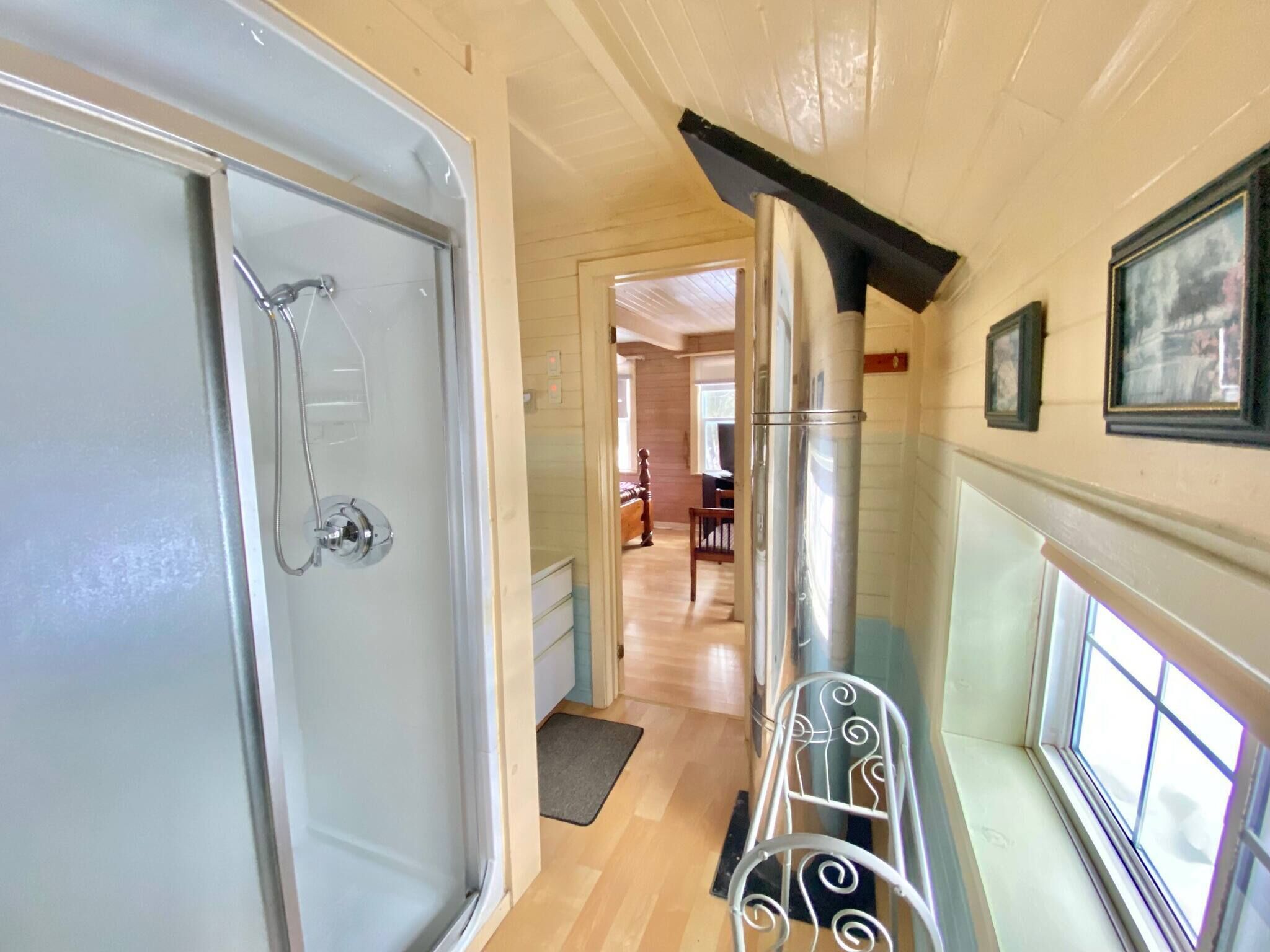 A bathroom with a glass shower enclosure, a wooden door, and a white bathtub.