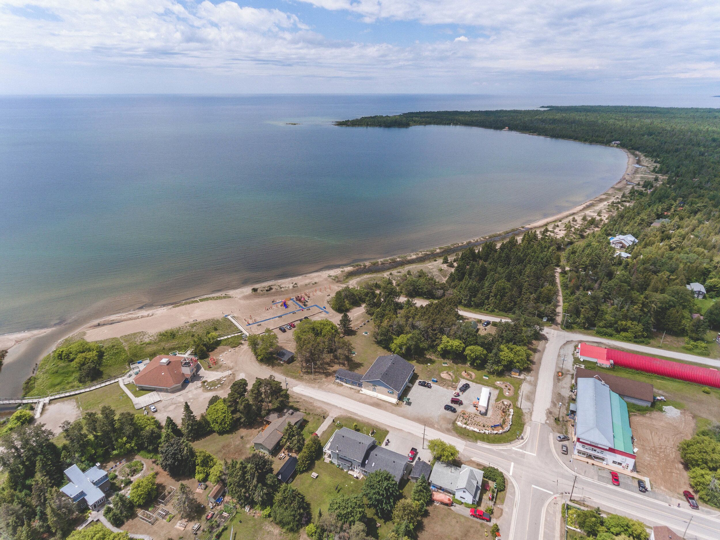 Vue aérienne d’une zone côtière avec une plage, des maisons et une route.