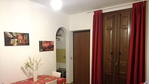 A dining area with a table and chairs, a red curtain, and a wooden door. - Colorful House Palermo (Palermo)