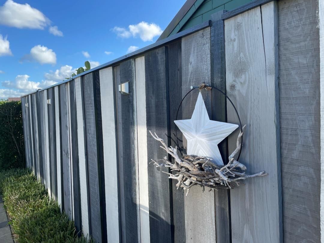 Una cerca de madera con un adorno en forma de estrella y una rama.