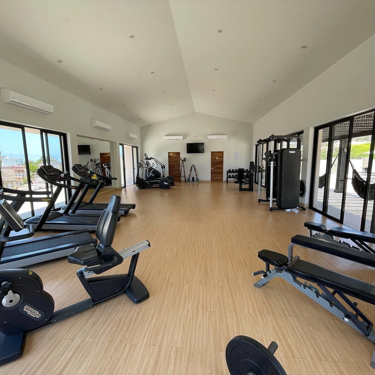 A spacious gym with treadmills, weight machines, and a large mirror.