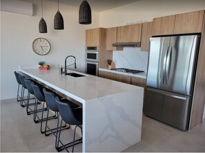 A modern kitchen with a marble island, stainless steel appliances, and wooden cabinets. - BRAND NEW Casa Sola Penthouse / Private Rooftop 3 Bedroom 4 Bed and Arch views (CABO SAN LUCAS-LOS CABOS)
