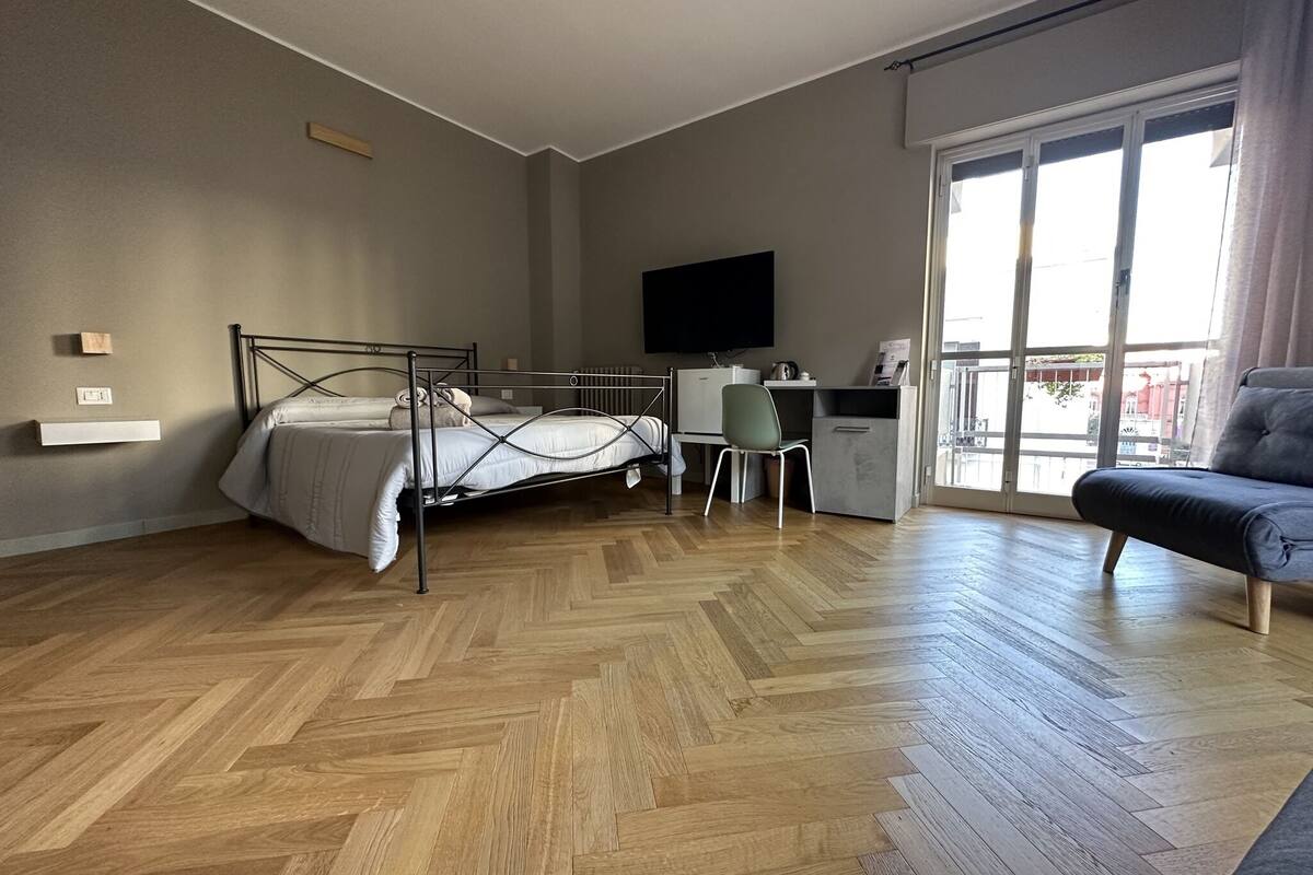 A modern bedroom with a bed, desk, chair, and a sofa.